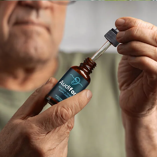 A person lifting the dropper out of an Audifort bottle